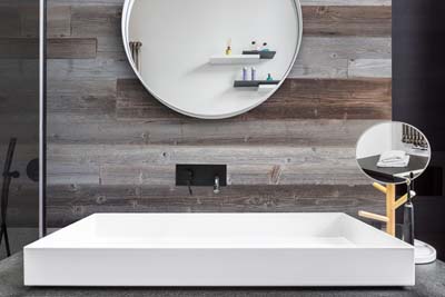 Badezimmer Innenraum mit grauen Holzplatten hinter morror und Waschbecken
